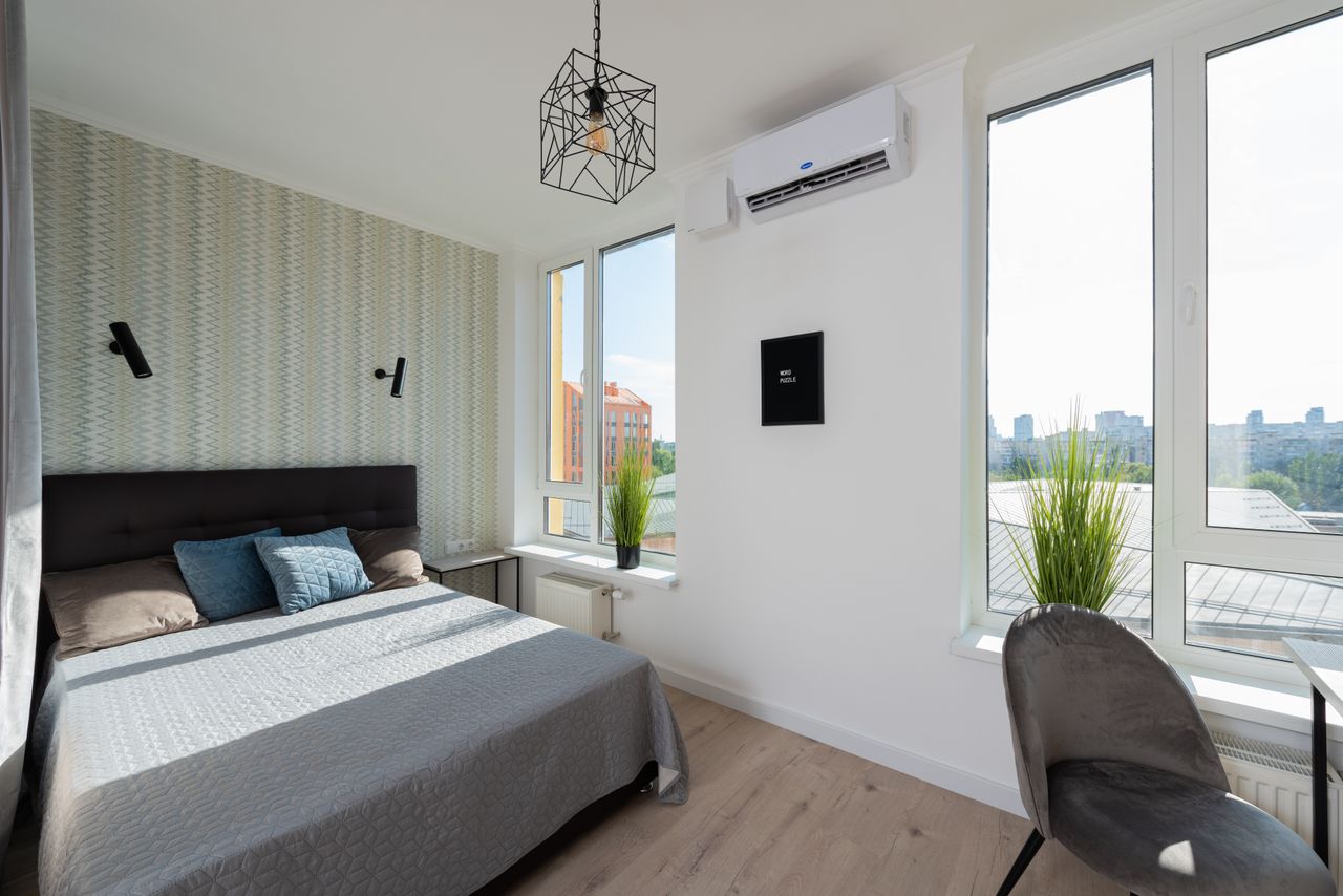 Crafting Captivating Headlines: Your awesome post title goes here Interior of modern light bedroom with pillows and blanket on bed near table and windows with potted green plants on windowsill next to chair
